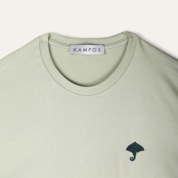 Close-up of the dark teal ray motif on the KAMPOS pale sage green T-shirt